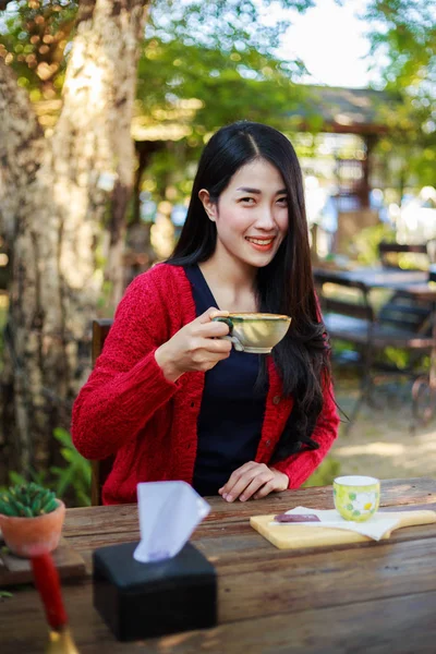 テーブルの上に座ってとガールのコーヒーのカップを飲む女性 — ストック写真