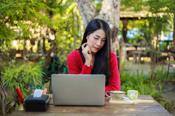 Femme utilisant un ordinateur portable et boire du café dans le jardin — Photo