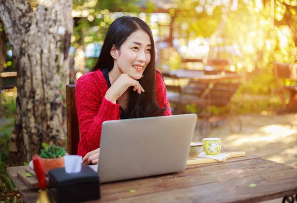 Femme utilisant un ordinateur portable et boire du café dans le jardin — Photo