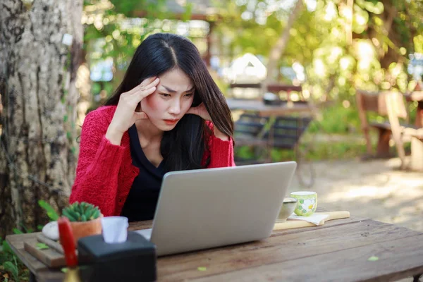 Femme inquiète en utilisant un ordinateur portable et boire du café dans le jardin — Photo