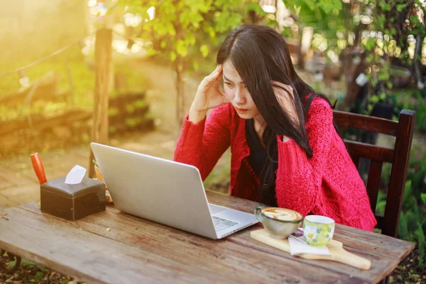 Orolig kvinna använder laptop och dricka kaffe i trädgården — Stockfoto