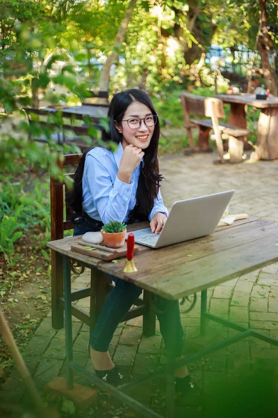 portrait of young woman with laptop and coffee in the garden