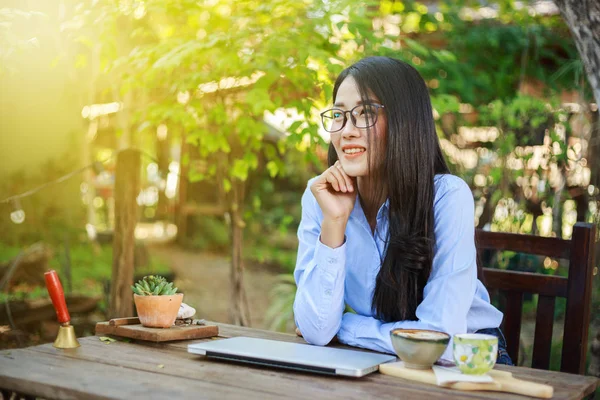 Porträtt av ung kvinna med laptop och kaffe i trädgården — Stockfoto