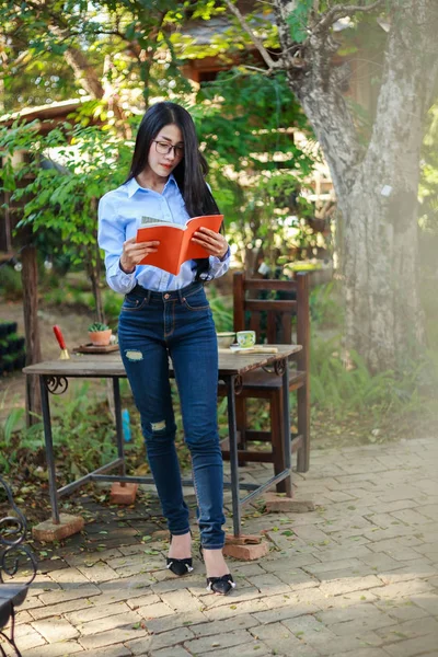 Stående kvinna läser en bok i trädgården — Stockfoto