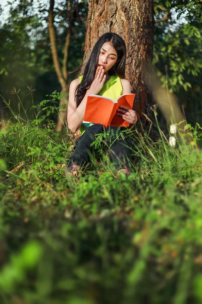 Förvånad kvinna läser en bok i trädgården — Stockfoto