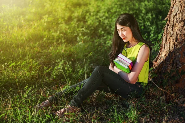 Kvinna sitter och håller en bok i parken — Stockfoto