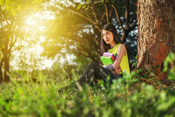 Kvinna sitter och håller en bok i parken — Stockfoto