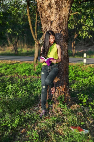 Kvinna stading på trädet och läsa en bok i parken — Stockfoto