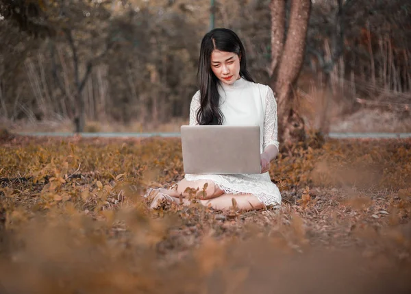 Vacker kvinna med laptop i parken — Stockfoto