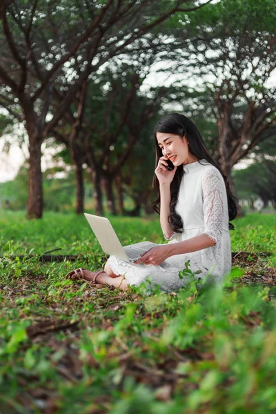 Vacker kvinna med laptop och ringa med mobiltelefon i th — Stockfoto