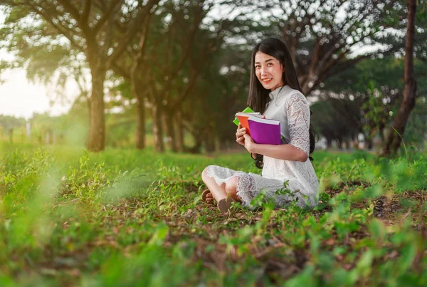 Ung kvinna håller en bok i parken — Stockfoto