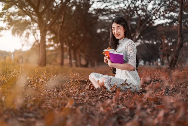 Ung kvinna håller en bok i parken — Stockfoto