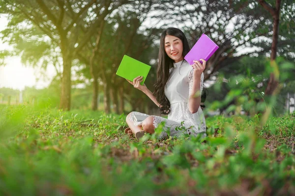 Ung kvinna håller en bok i parken — Stockfoto