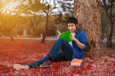 oturma ve parkta bir kitap okuma genç adam