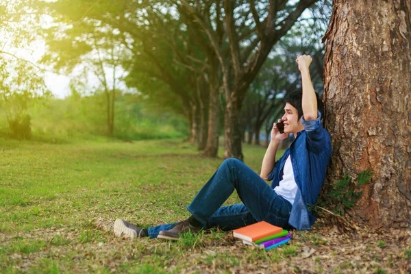 Glad man pratar i mobiltelefon med hand upp i park — Stockfoto