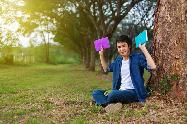 Giovane seduto e con in mano un libro nel parco — Foto Stock