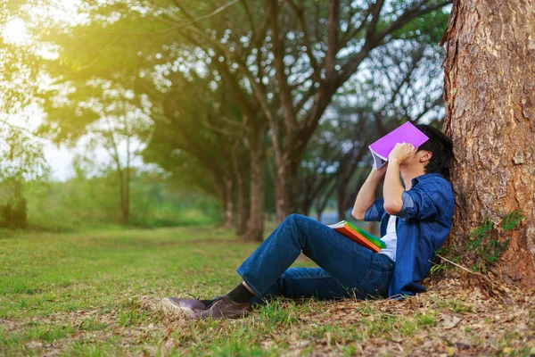 Ung man i stressituation när man läser en bok i parken — Stockfoto