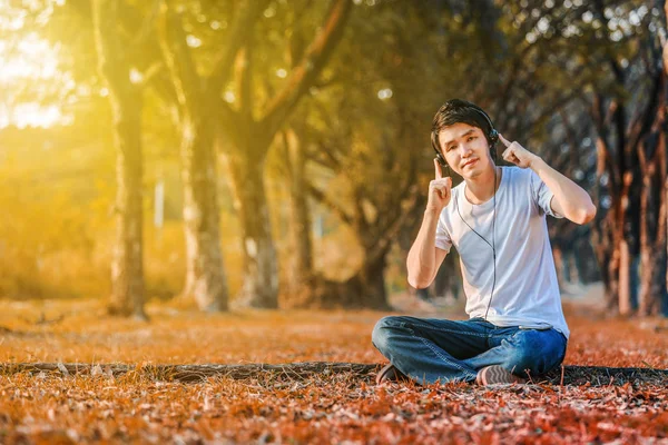 Jeune homme écoutant de la musique avec des écouteurs mobiles dans le parc — Photo