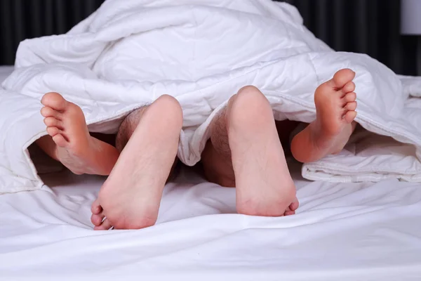 Par pés visto de baixo cobertor na cama — Fotografia de Stock