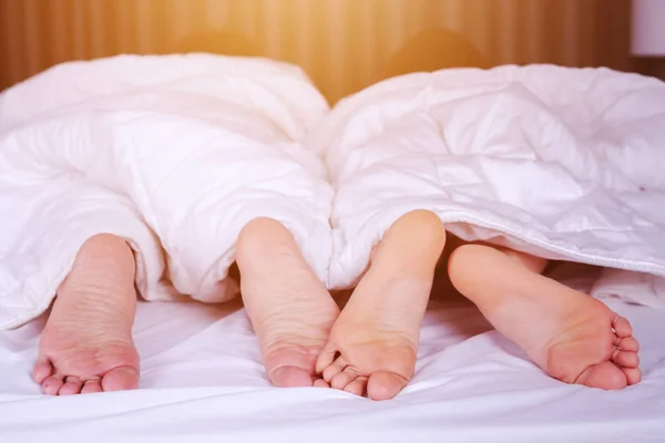 Close up van vier voeten in bed — Stockfoto