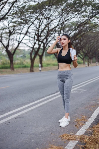 Young sporty woman resting and wiping her sweat with a towel aft — Stock Photo, Image