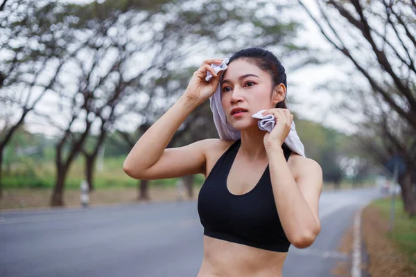 Joven mujer deportiva descansando y limpiando su sudor con una toalla a popa — Foto de Stock