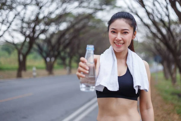 Young sporty woman with bottle of water in park — Stock Photo, Image