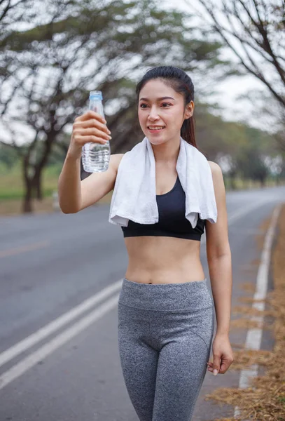 Молодая спортсменка с бутылкой воды в парке — стоковое фото
