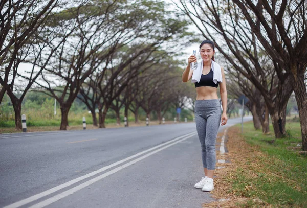 Jeune femme sportive avec bouteille d'eau dans le parc — Photo