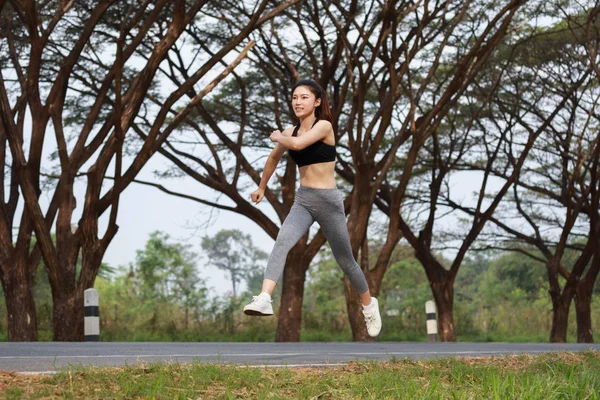 Спортивная женщина бегает и прыгает в парке — стоковое фото