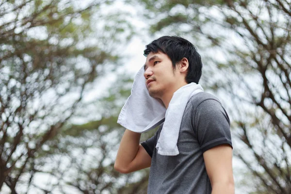 stock image young sporty man resting and wiping his sweat with a towel after