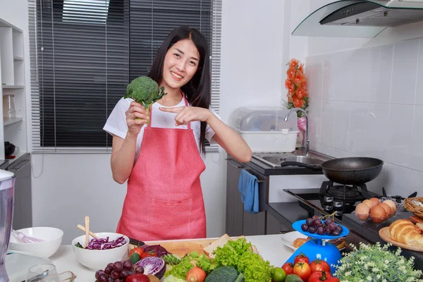 Mulher segurando brócolis verde fresco na sala de cozinha — Fotografia de Stock