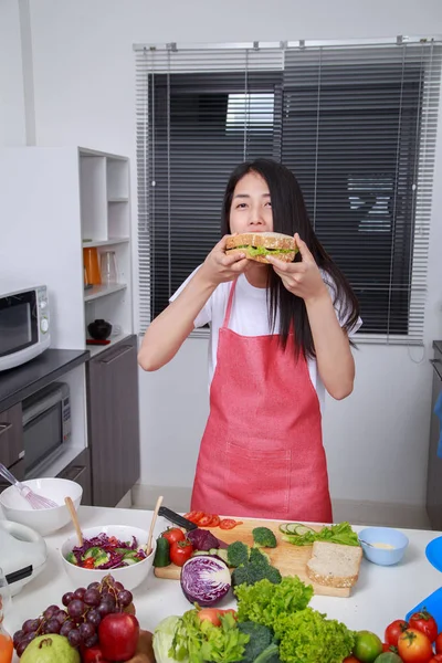 Mulher comendo um sanduíche na sala de cozinha — Fotografia de Stock