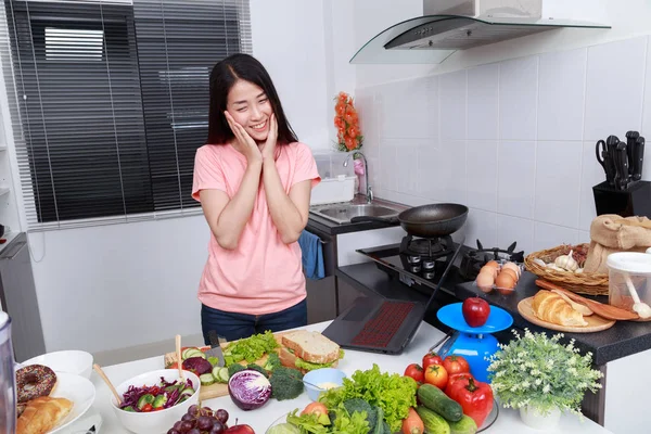 Happy woman cooking and looking with laptop in kitchen room — Stock Photo, Image