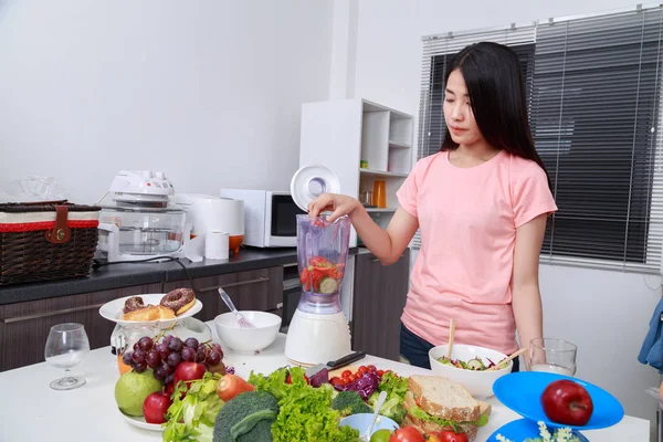 Mulher fazendo smoothies vegetais com liquidificador na cozinha — Fotografia de Stock