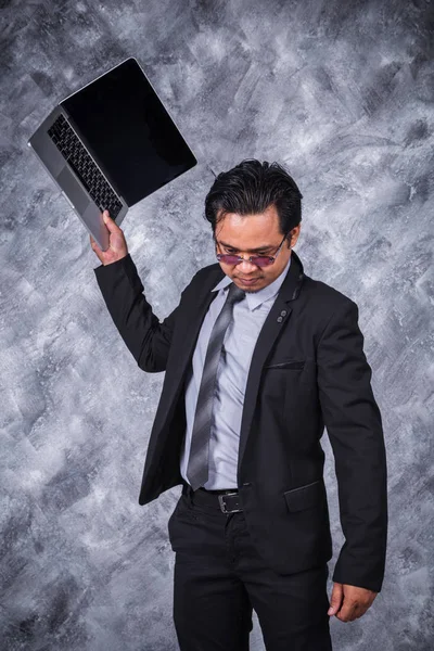 angry business man is throwing away his laptop