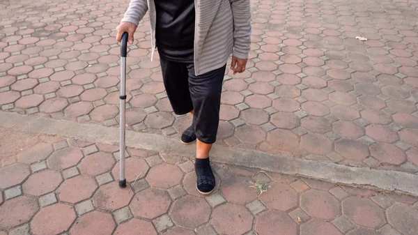 Piernas de mujer mayor caminando con bastón en el parque — Foto de Stock