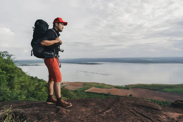 Man traveler with backpack standing on edge of cliff, on a top o — Stock Photo, Image