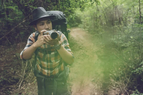 Homem viajante com mochila usando câmera para tirar uma foto no f — Fotografia de Stock