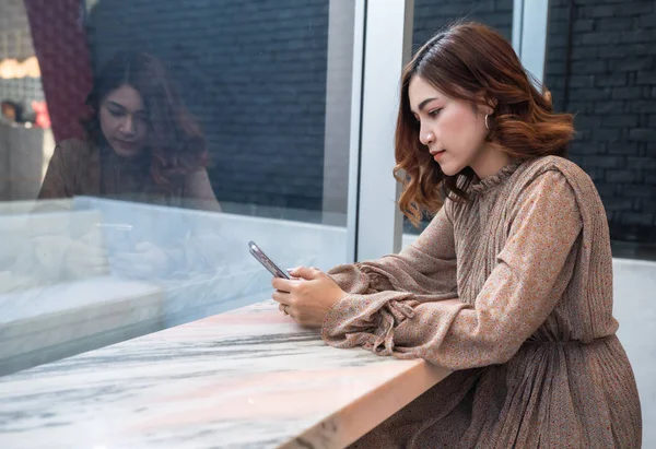 Mujer usando en su teléfono inteligente en la ventana — Foto de Stock