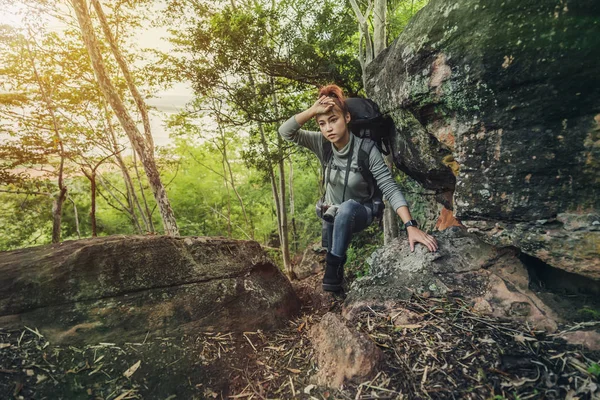 tired hiker woman climbing up in forest