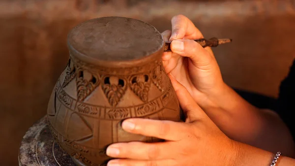 Hands make potter a decorative pattern on earthenware — Stock Photo, Image