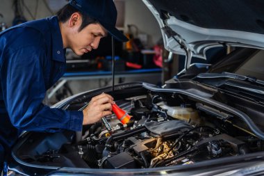 Erkek tamirci el feneri tutarken araba motoru sorununu kontrol ediyor.