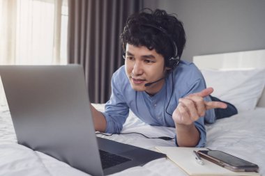 İş adamı kulaklık takıyor. Ev konseptinden çalışmak için laptoptan bilgisayara arıyor.