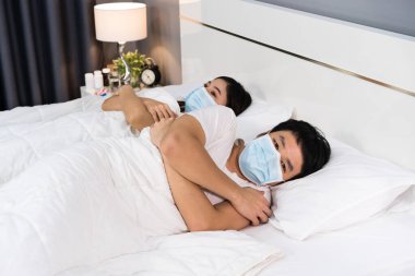 Hasta çift yatakta üşüyorlar ve koronavirüs için tıbbi maske takıyorlar (covid-19)
