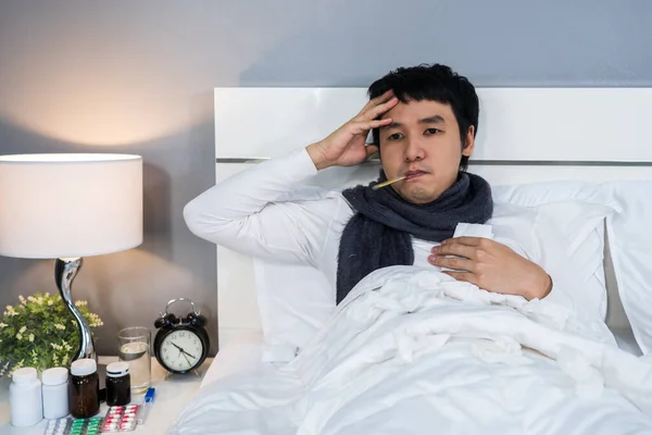 sick man is headache and using thermometer to checking his temperature in a bed
