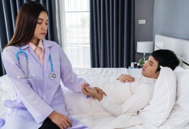 Doktor nabzını kontrol ederken hasta bir adam yatakta yatıyor.