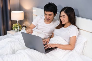 Çift dizüstü bilgisayarı yatakta birlikte kullanıyor.