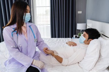 Hasta bir adam yatakta yatarken doktor nabzını kontrol ediyor olmalı. İnsanlar koronavirüsten (covid-19) korunan tıbbi maske takıyor olmalı.