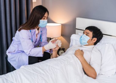 Doktor yatakta hasta bir adamla konuşuyor ve danışmanlık yapıyor, insanlar koronavirüsten korunmak için tıbbi maske takıyor olmalı (covid-19).